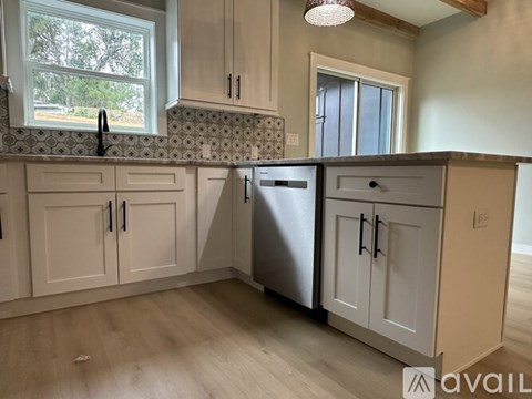 A kitchen with a stainless steel dishwasher and white cabinets.