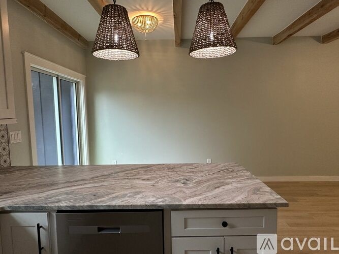 A kitchen with a marble countertop and two hanging lights.