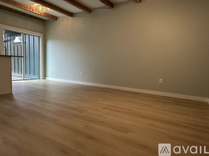 A room with wooden flooring and a window with bars on it.