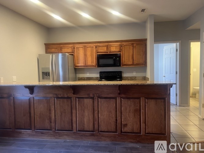 A kitchen with wooden cabinets and a stainless steel refrigerator.