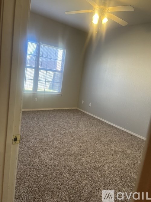 A room with a ceiling fan and a window letting in sunlight.