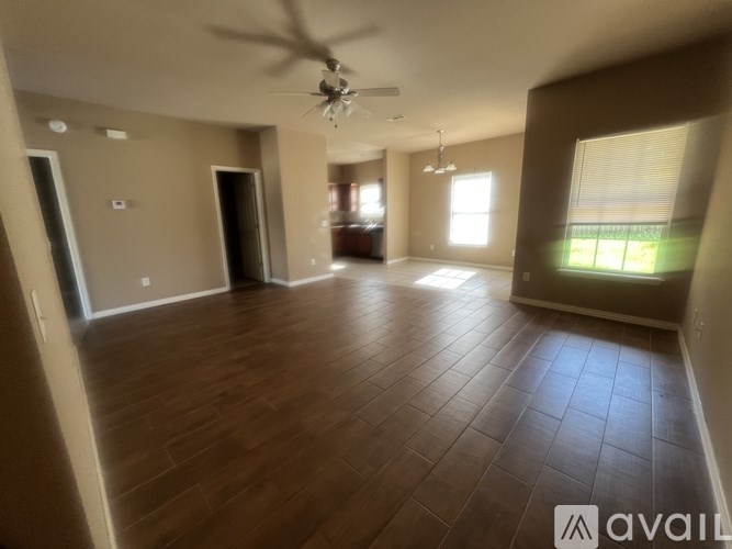 A spacious room with wooden flooring and a ceiling fan.