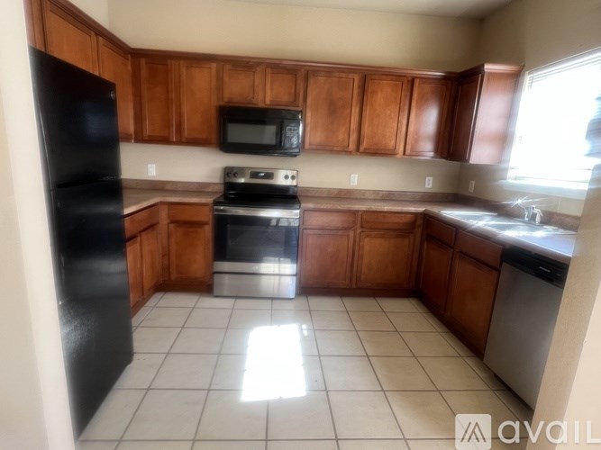 A kitchen with wooden cabinets and a black refrigerator.