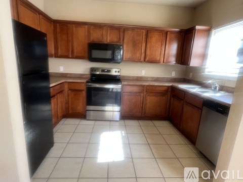 A kitchen with wooden cabinets and a black refrigerator.