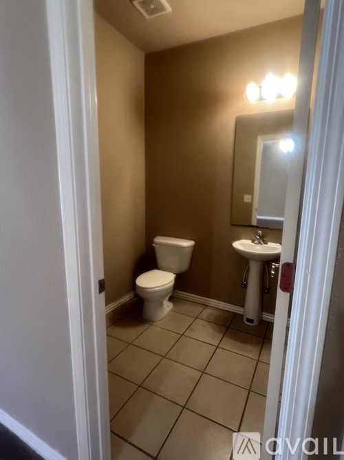 A bathroom with a toilet, sink, and mirror.