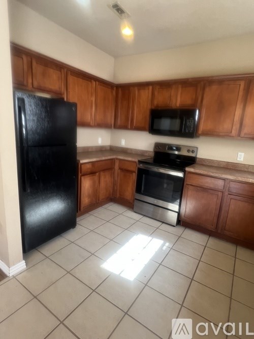 A kitchen with a black fridge, microwave, oven and stove top.