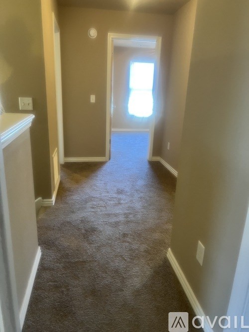 A hallway with a carpeted floor and a door at the end.