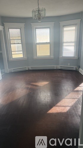 A room with wooden floors and three windows.