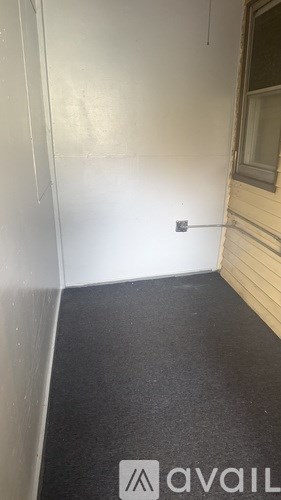 A room with a black carpet and a window.