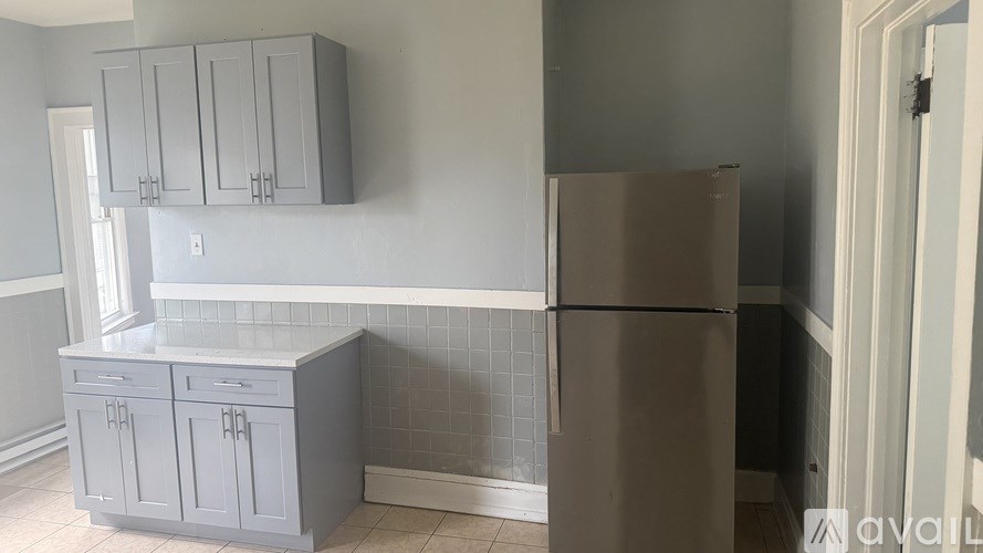 A kitchen with a refrigerator, cabinets, and a tiled backsplash.