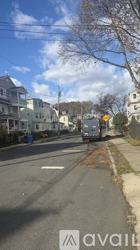 A street view with houses on the side and a car driving down the road.