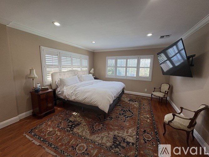 A bedroom with a large bed, a rug, and a television.