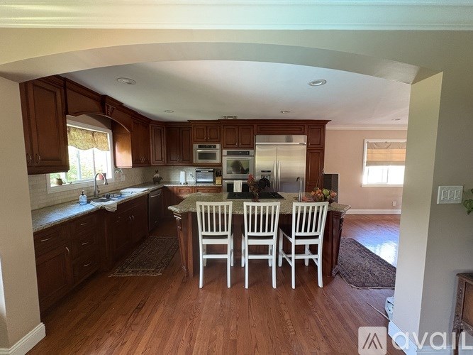 A kitchen with wooden floors and white chairs.
