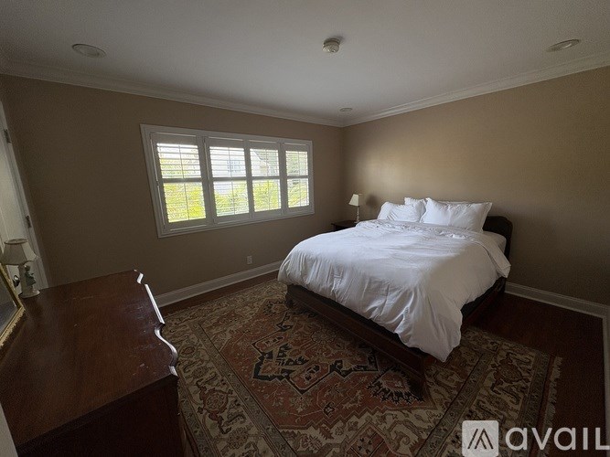 A bedroom with a bed, dresser, and window.