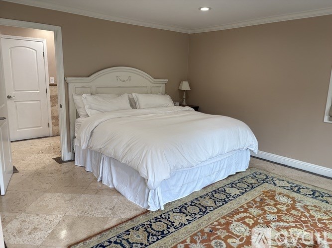 A bedroom with a large bed and a rug on the floor.