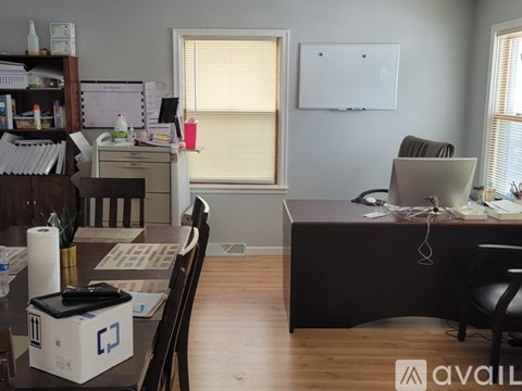 A room with a desk, chair, and a whiteboard on the wall.