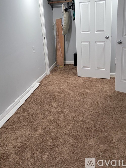 A room with a carpeted floor and a white door.