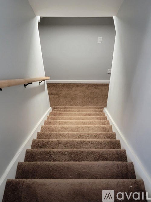 A staircase with a carpeted runner and a wooden handrail.