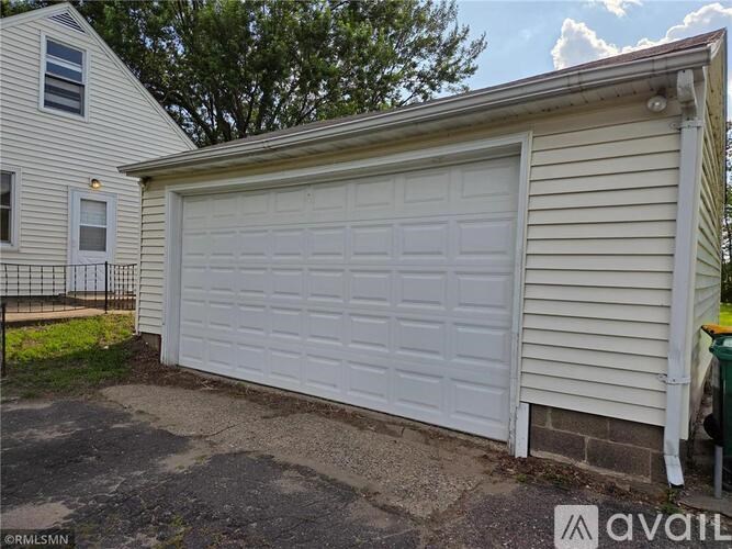 A white garage door is closed and appears to be made of wood.