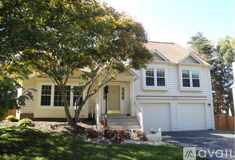 A two-story house with a white garage door and a tree in front.