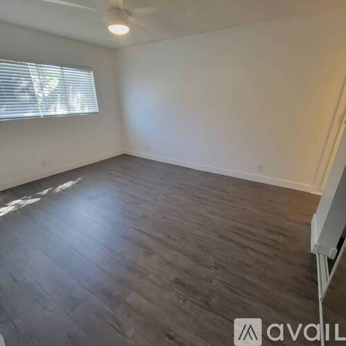 A room with wooden flooring and a window with blinds.