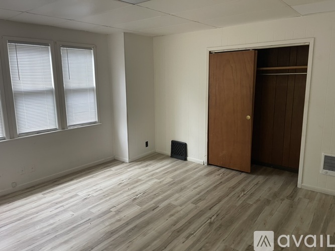A room with a wooden door and a window with blinds.