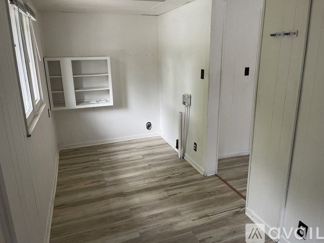 A room with wooden flooring and white walls.