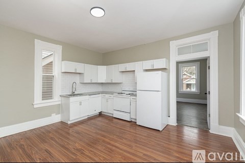 A kitchen with white cabinets and a wooden floor.