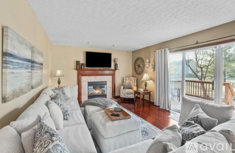 A living room with a grey couch and a fireplace.