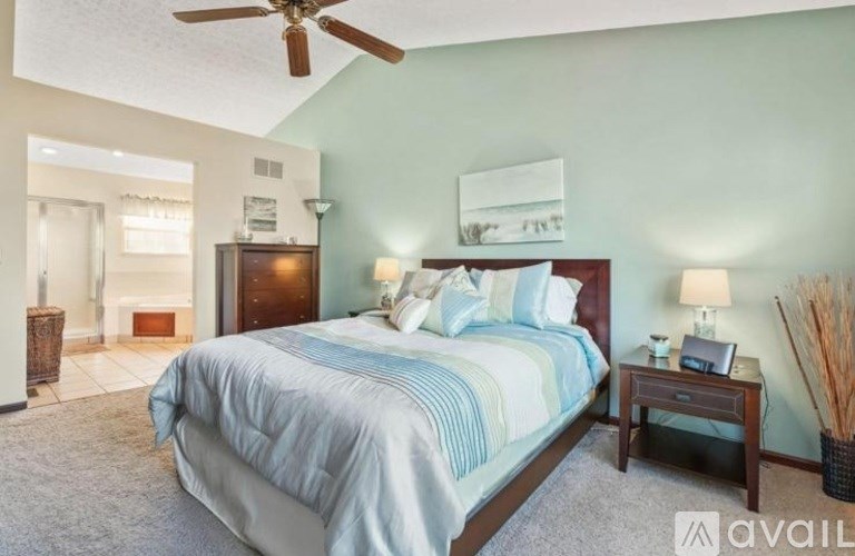 A bedroom with a large bed and a ceiling fan.