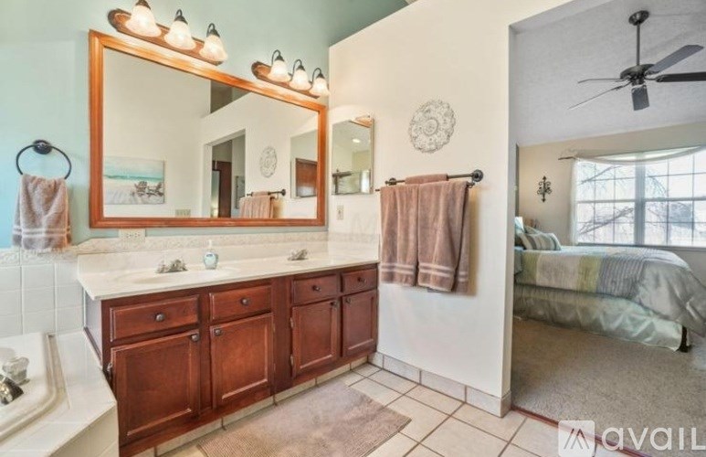 A bathroom with a large mirror, wooden cabinets, and a fan.