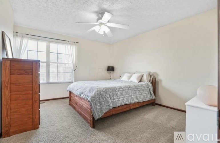 A bedroom with a bed, dresser, and window.