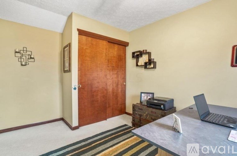 A room with a laptop on a desk and a wooden door.