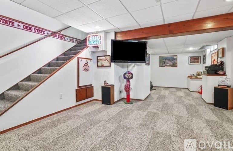 A room with a staircase and a flat screen TV mounted on the wall.