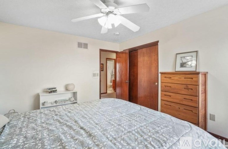 A bedroom with a bed, dresser, and ceiling fan.