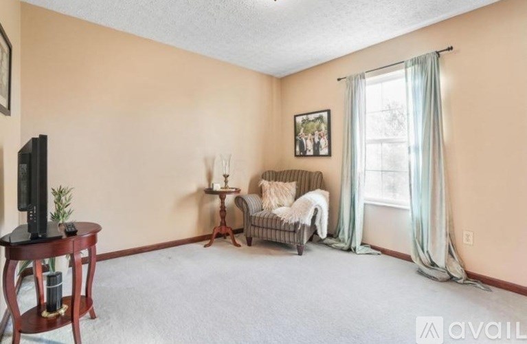 A living room with a television, a chair, and a small table.