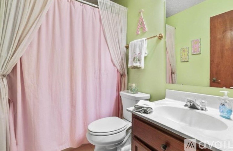 A bathroom with a pink shower curtain and a white toilet.