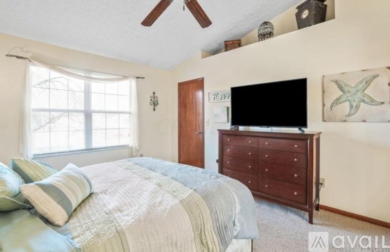 A bedroom with a bed, dresser, and a window.