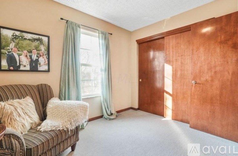 A living room with a couch, a picture on the wall, and a window with curtains.