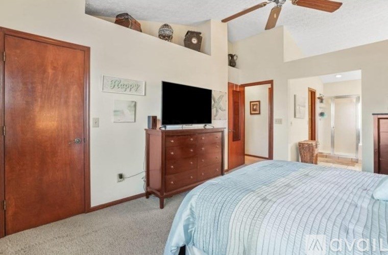 A bedroom with a bed, dresser, and a television.