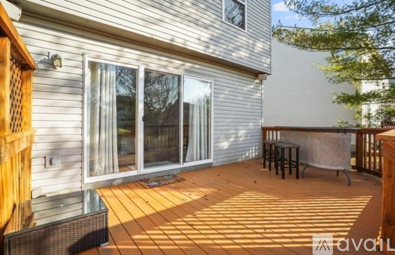 A wooden deck with a table and chairs is in front of a house.