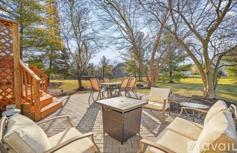 A patio with a table and chairs surrounded by trees.