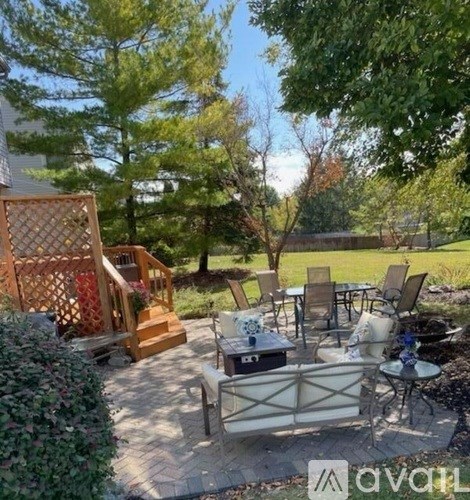A patio with a table and chairs surrounded by greenery.