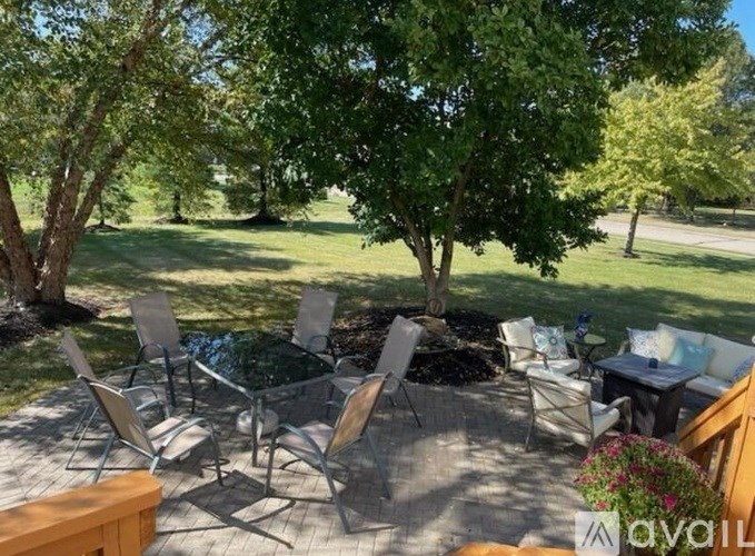A patio with chairs and a table surrounded by trees.