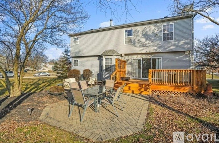 A house with a grey exterior and a patio with chairs and a table.