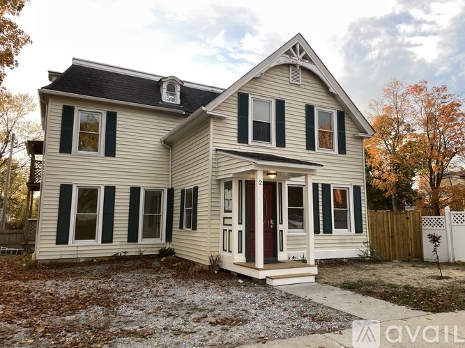 A two-story house with a white exterior and black shutters.