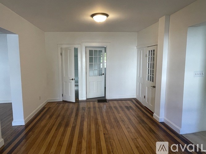 A room with wooden floors and white walls, with a door in the middle.