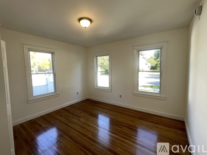 A room with wooden floors and three windows.