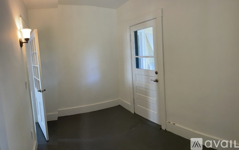 A room with a white door and a window with a white curtain.