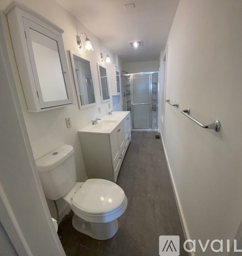 A bathroom with a toilet, sink, and mirrors.